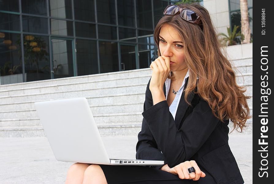 Business woman sitting on the steps with notebooks and monitors the exchange
