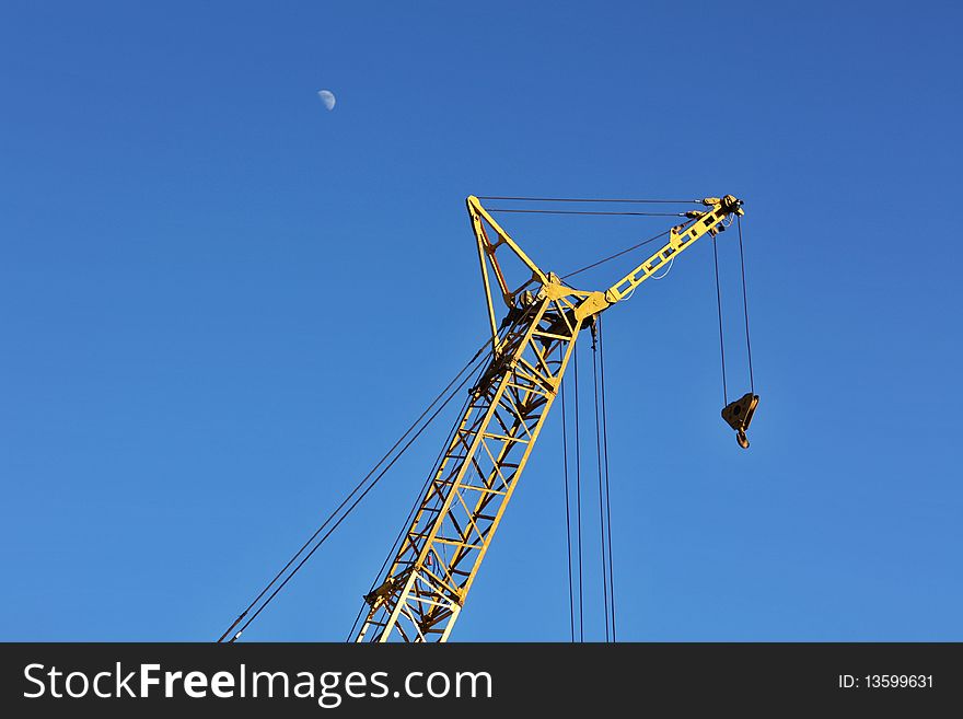 The yellow crane and moon in the blue sky horizontal. The yellow crane and moon in the blue sky horizontal