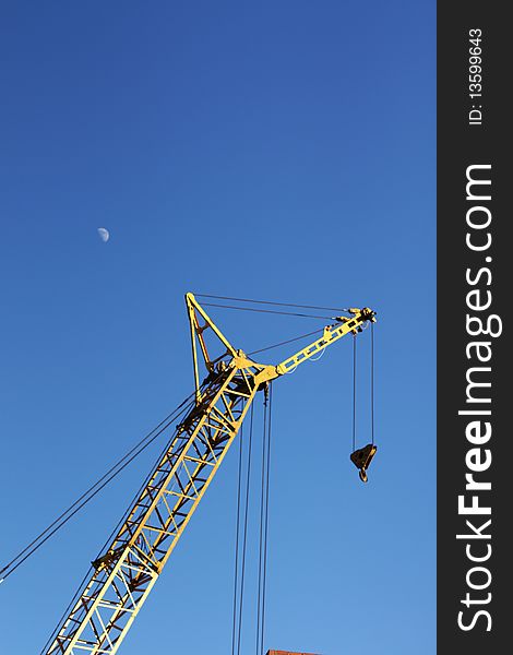 The yellow crane and moon in the blue sky vertical. The yellow crane and moon in the blue sky vertical