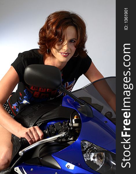 A brunette girl sitting on a blue motorcycle. A brunette girl sitting on a blue motorcycle