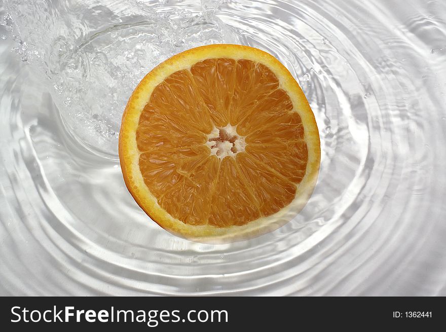 Slice of orange splashing into water