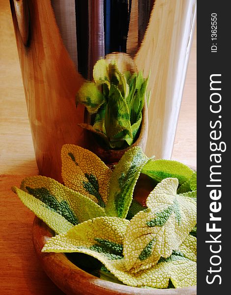 Sage leaves in a wooden bowl reflected in metal mug. Sage leaves in a wooden bowl reflected in metal mug