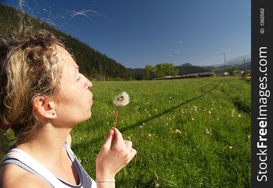 Girl blowing seeds out of a dandelion
