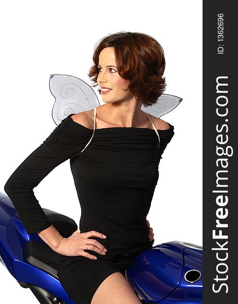 A brunette girl leaning on a blue motorcycle with black dress and wings. A brunette girl leaning on a blue motorcycle with black dress and wings