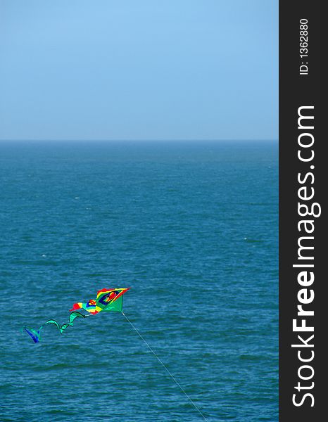 A colorful kite flying in the sea breeze. A colorful kite flying in the sea breeze