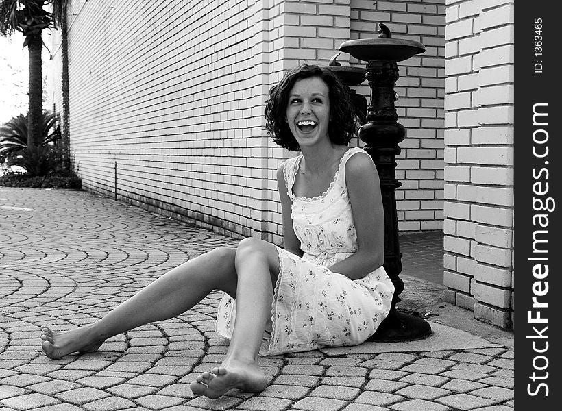 Picture of a young teen girl laughing while sitting on the street. Picture of a young teen girl laughing while sitting on the street