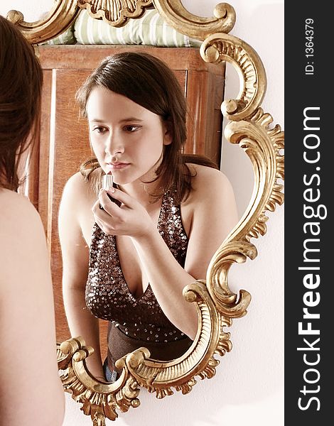 Auburn-haired girl, young woman putting make up in front of  a mirror