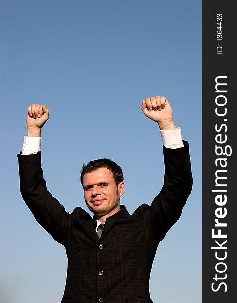 Young businessman with a blue sky behind him, raising his hands. Young businessman with a blue sky behind him, raising his hands