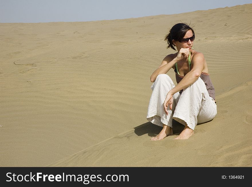Girl in the dunes in Maspalomas contemplating life. Girl in the dunes in Maspalomas contemplating life.