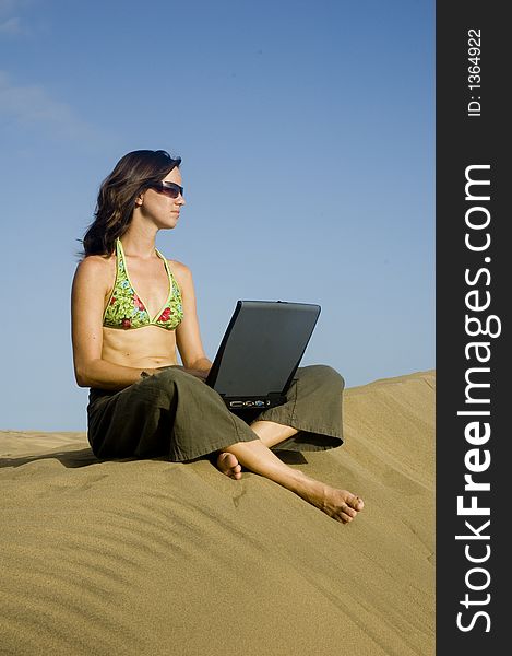 Girl working on her laptop in the dunes in Gran Canaria. Girl working on her laptop in the dunes in Gran Canaria