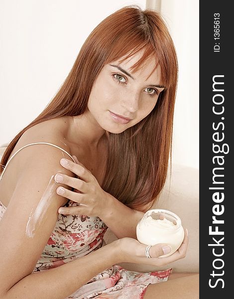 Red-haired young girl, woman putting some cream