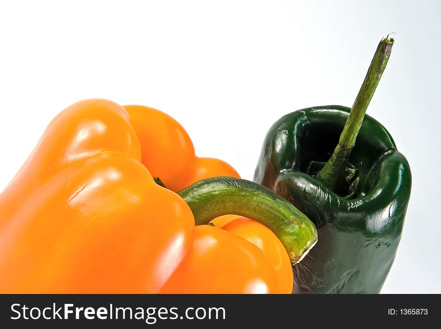Angled view of two peppers, one yellow, one green