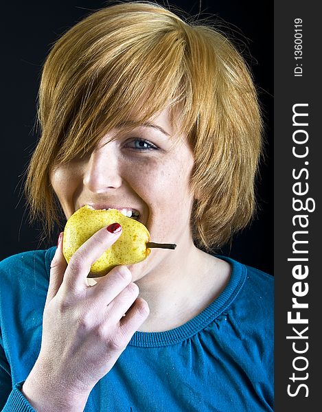 Cute blond girl eating a pear. Cute blond girl eating a pear