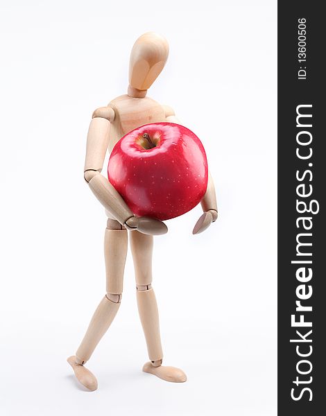 Wooden man holding a large red apple. Isolated over white