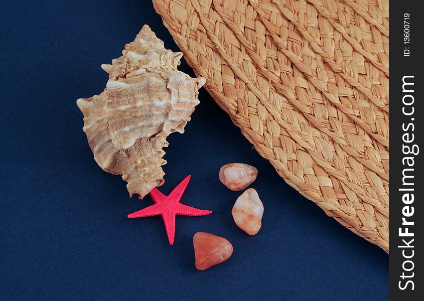 Shell, pebbles and sun hat on dark blue background. Shell, pebbles and sun hat on dark blue background