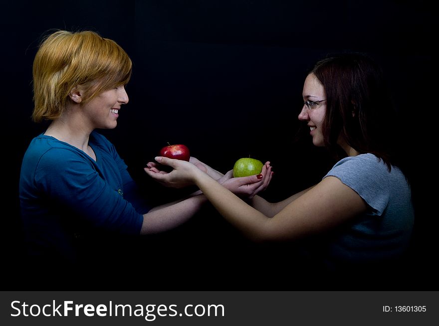 Two girls sharing colorful apples