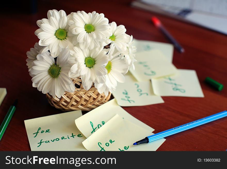 An image of basket with white daisies on the desk