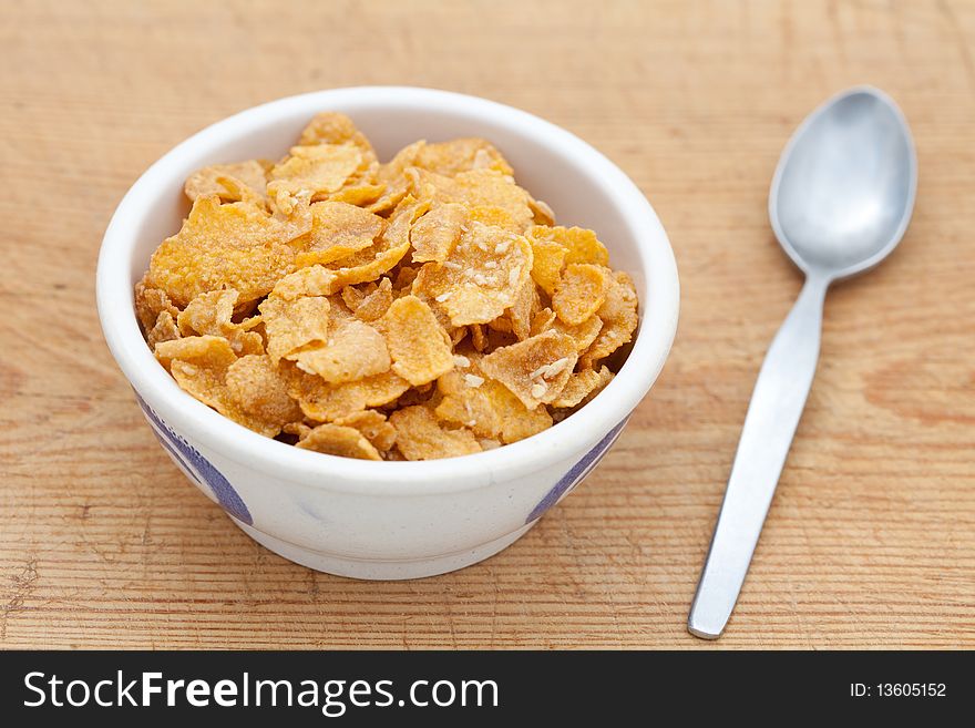 Cornflakes in a white bowl with a spoon