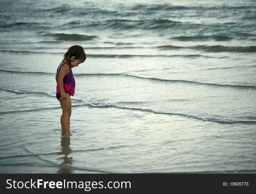 Young girl playing on a beach, with small waves. Young girl playing on a beach, with small waves