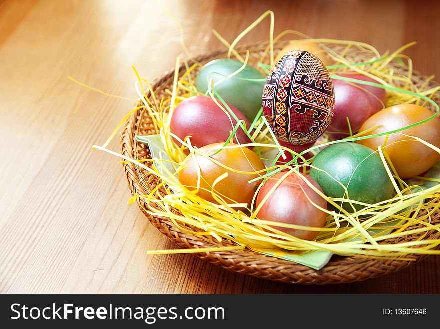 Easter painted eggs in traditional basket on table