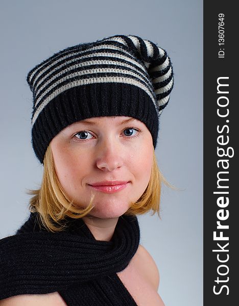 Portrait of a young pretty girl in black and white striped hat and scarf