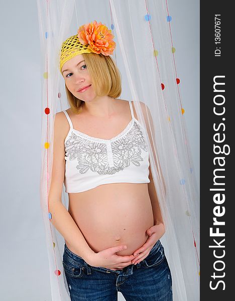 Young cute blonde pregnant girl with a flower on her head