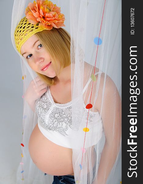 Young cute blonde pregnant girl with a flower on her head