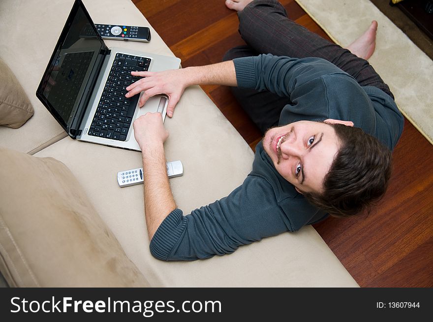 Portrait of a smiling man working on a laptop at home sitting on the couch. Portrait of a smiling man working on a laptop at home sitting on the couch