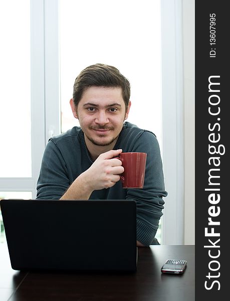 Portrait of a man working on a laptop at home drinking coffee. Portrait of a man working on a laptop at home drinking coffee