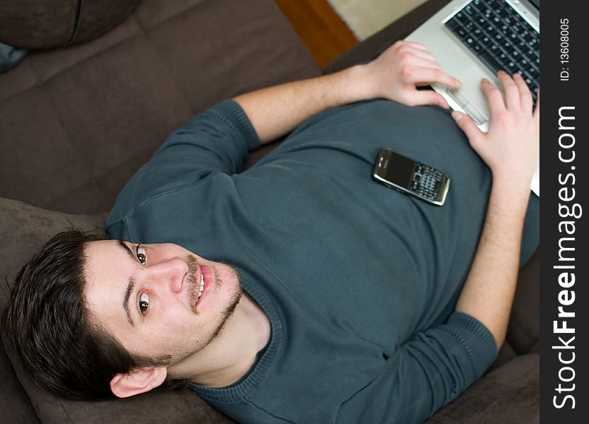 Portrait of a man working on a laptop at home lying on the couch. Portrait of a man working on a laptop at home lying on the couch