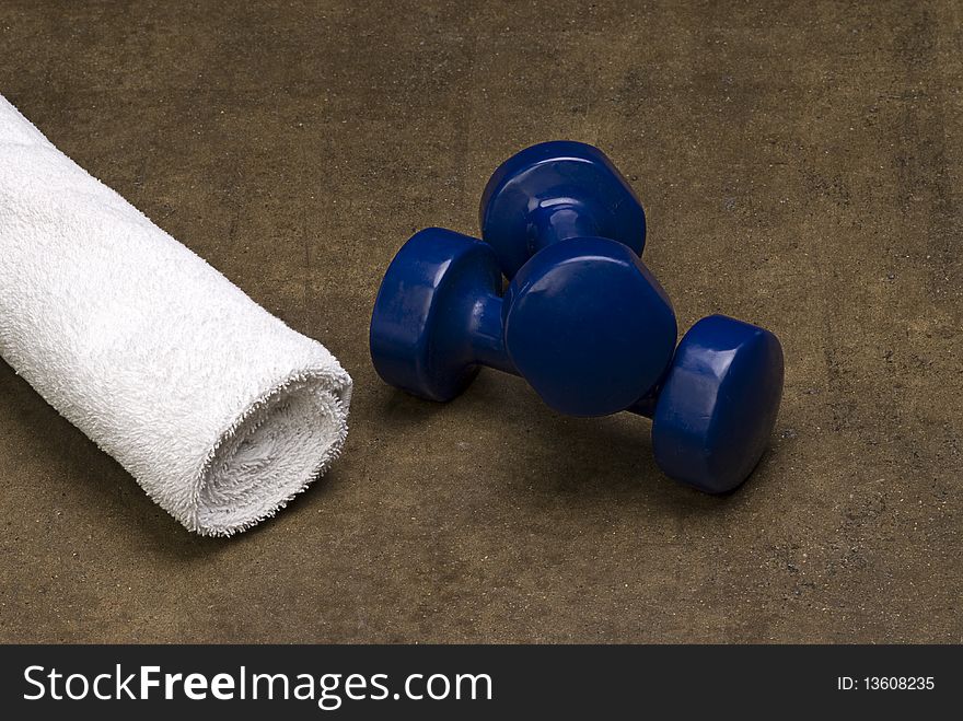 Blue dumbbells and a white towel isolated on a grungy textured background