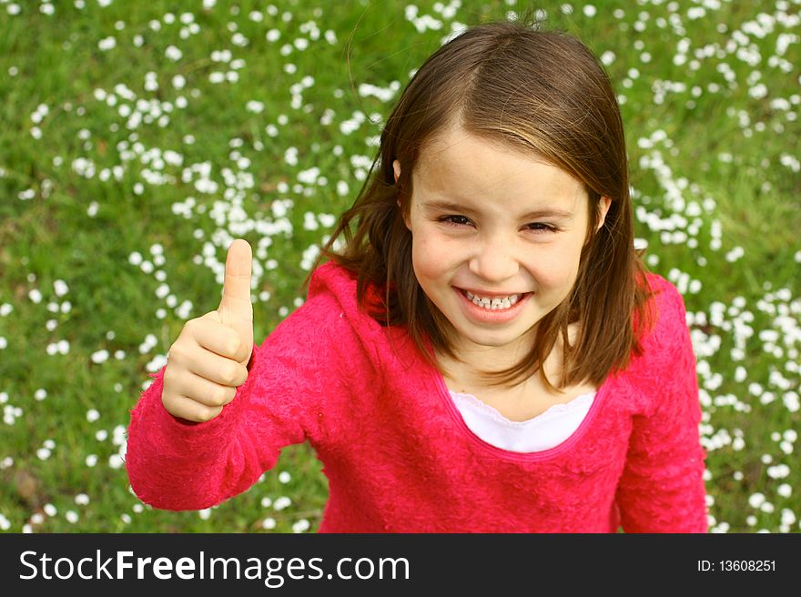 Cute little girl with thumb up and springtime grassy field. Cute little girl with thumb up and springtime grassy field.