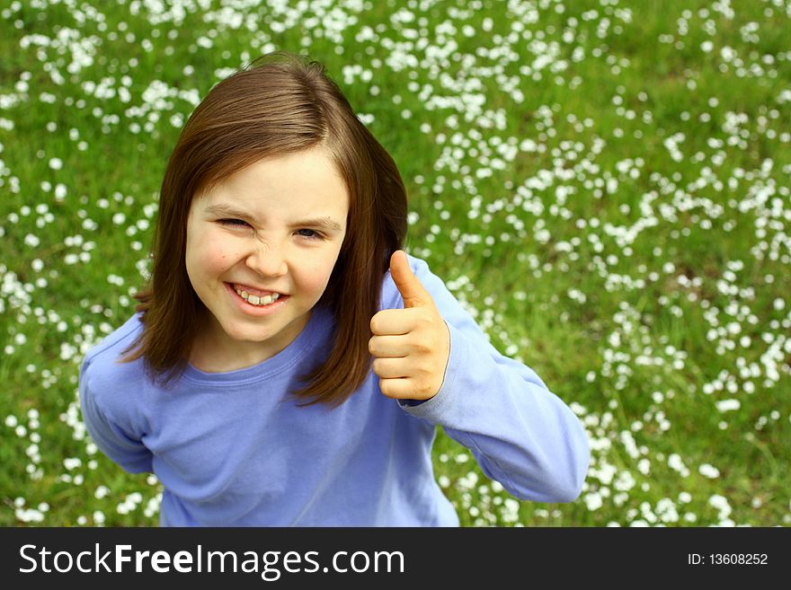 Cute little with thumb up and springtime grass in background. Cute little with thumb up and springtime grass in background.