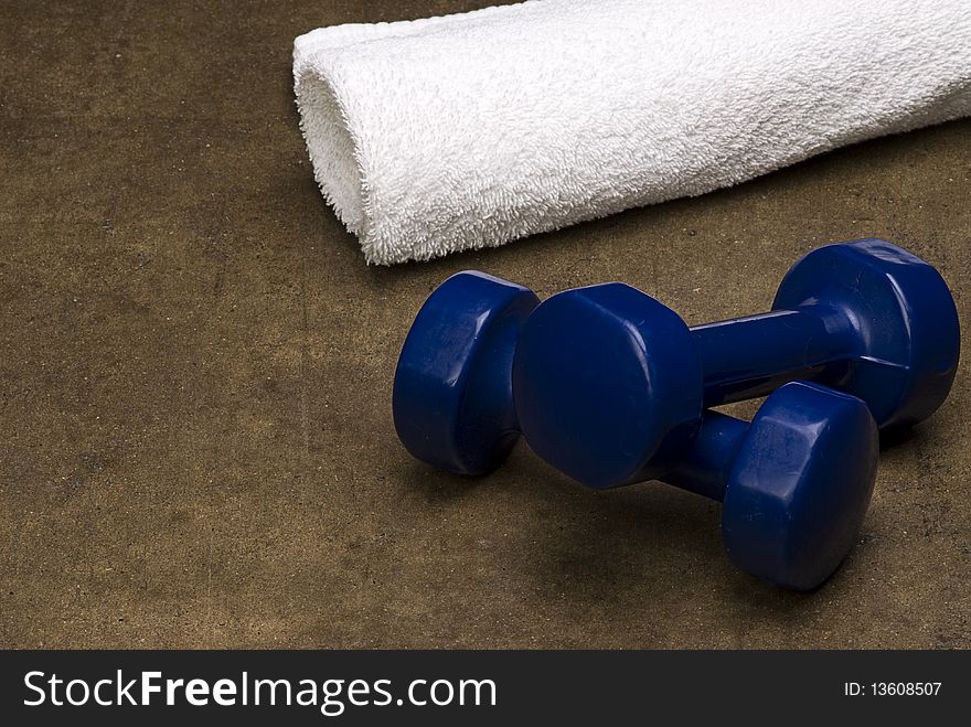 Blue dumbbells with a towel isolated on grunge textured background. Blue dumbbells with a towel isolated on grunge textured background