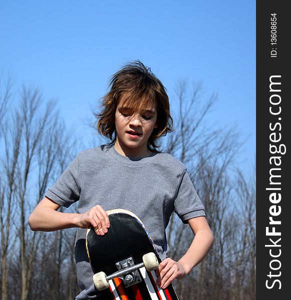 Young teen looking down at skateboard. Young teen looking down at skateboard.