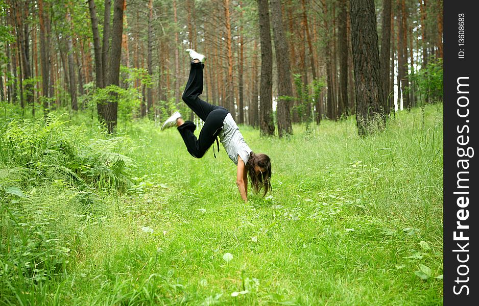 The girl jumping on a green grass in a wood. The girl jumping on a green grass in a wood