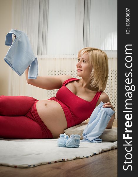 Happy pregnant woman holding baby clothes. Happy pregnant woman holding baby clothes