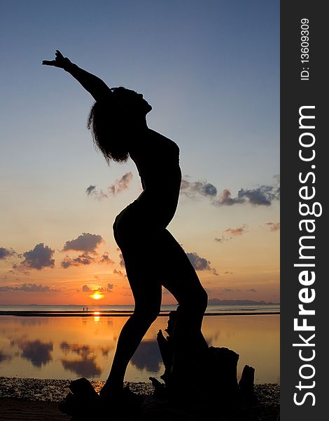 A silhouette of a woman facing the sunset in a yoga pose. A silhouette of a woman facing the sunset in a yoga pose