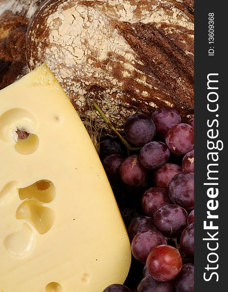 Close up with cheese, red grapes and bread in background. Close up with cheese, red grapes and bread in background