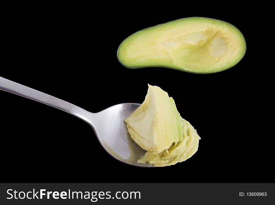 Avocado and spoon on the black. Avocado and spoon on the black.