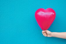 Young Caucasian Woman Girl Holds In Stretched Hand Bright Pink Heart Shape Air Balloon On Turquoise Wall. Valentine Royalty Free Stock Photo