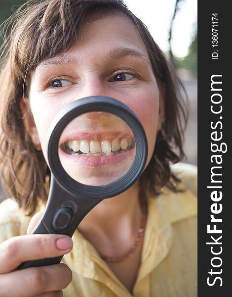 Woman with magnifier shows her crooked teeth.