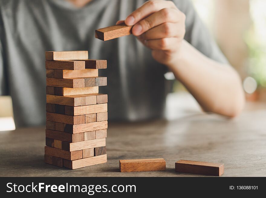 The Risk Will Happen.Hand Of Engineer Playing A Blocks Wood Game On Wood Table Vintage Tone. Architectural Project .as Background