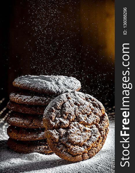A stack of cookies dusted with icing sugar on a dark background