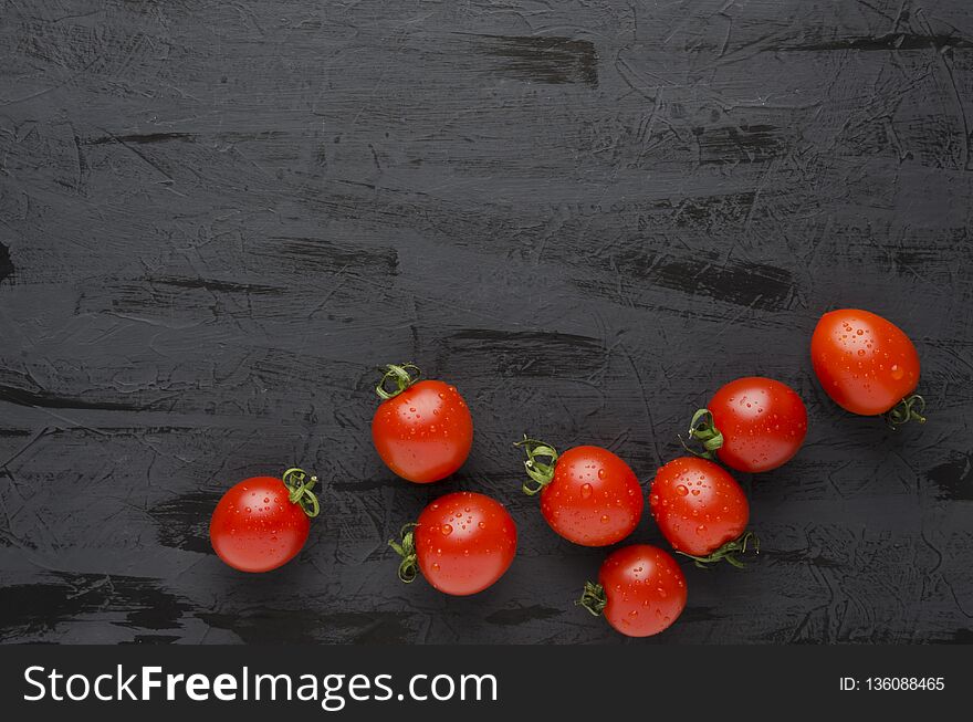 Delicious fresh tomatoes and salt on black table