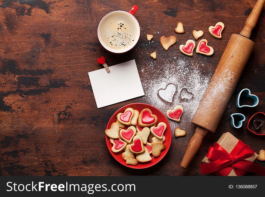 Valentine`s day greeting card with cooking heart shaped cookies on wooden background. Top view with space for your greetings. Flat lay