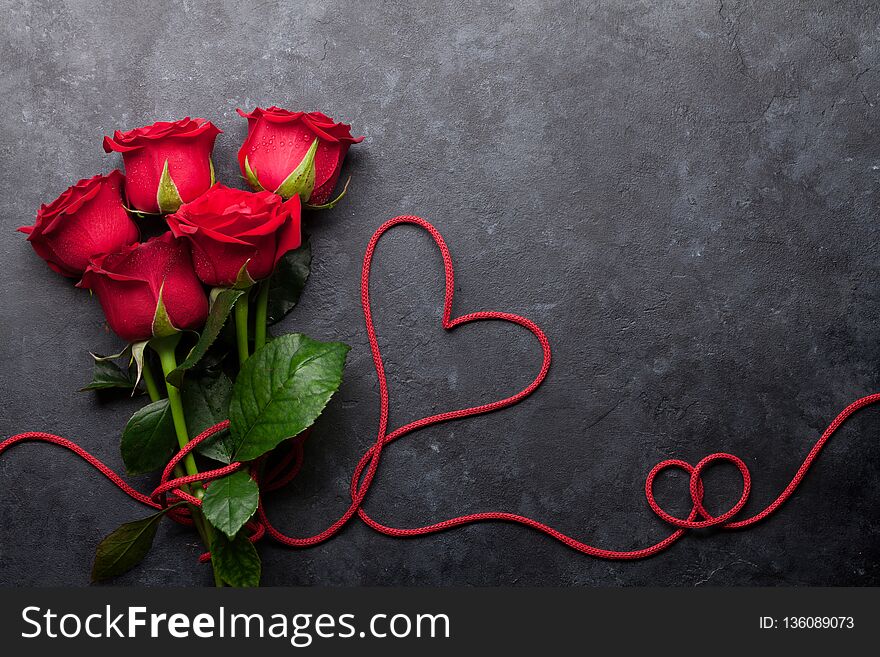 Valentine`s day greeting card with red rose flowers bouquet on stone background. Top view with space for your greetings. Valentine`s day greeting card with red rose flowers bouquet on stone background. Top view with space for your greetings