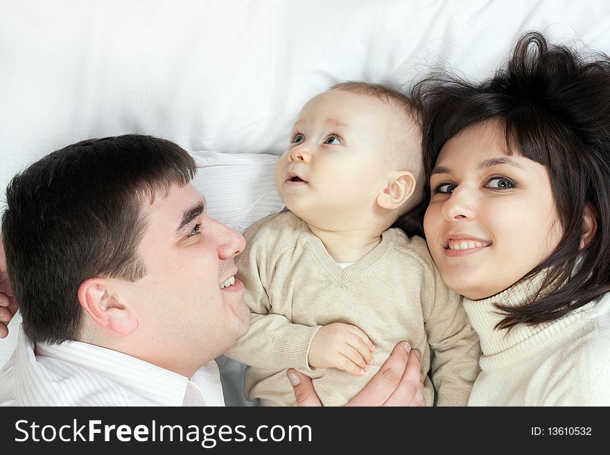 Happy family home: father, mother and baby lying on the floor and playing. Happy family home: father, mother and baby lying on the floor and playing
