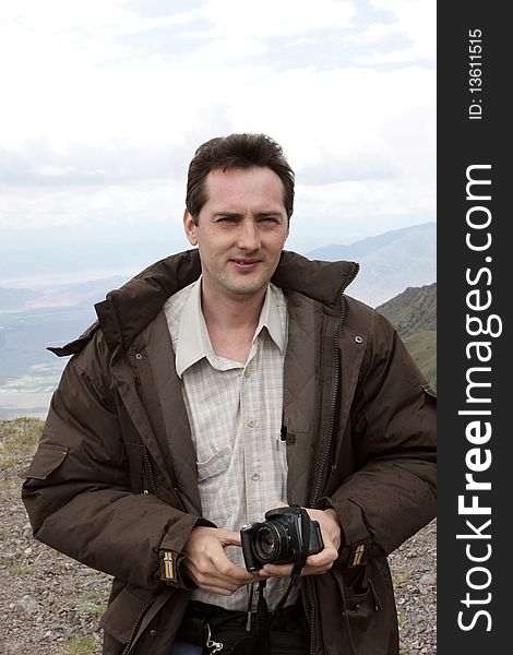 The man poses with camera in mountains, Kyrgyzstan