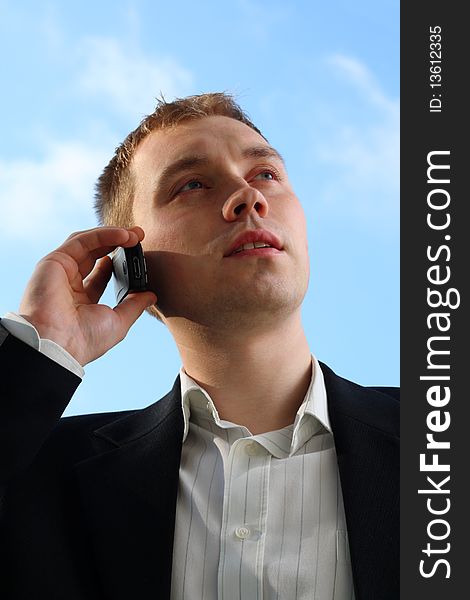 Portrait of young, handsome businessman using a cellphone, looking on the sky. Portrait of young, handsome businessman using a cellphone, looking on the sky
